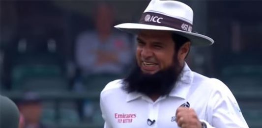 Cricket umpire with a beard, wearing an ICC hat, smiling and celebrating during a match. The image captures his joyful reaction after making a significant decision, highlighting his role in setting cricket umpire records.